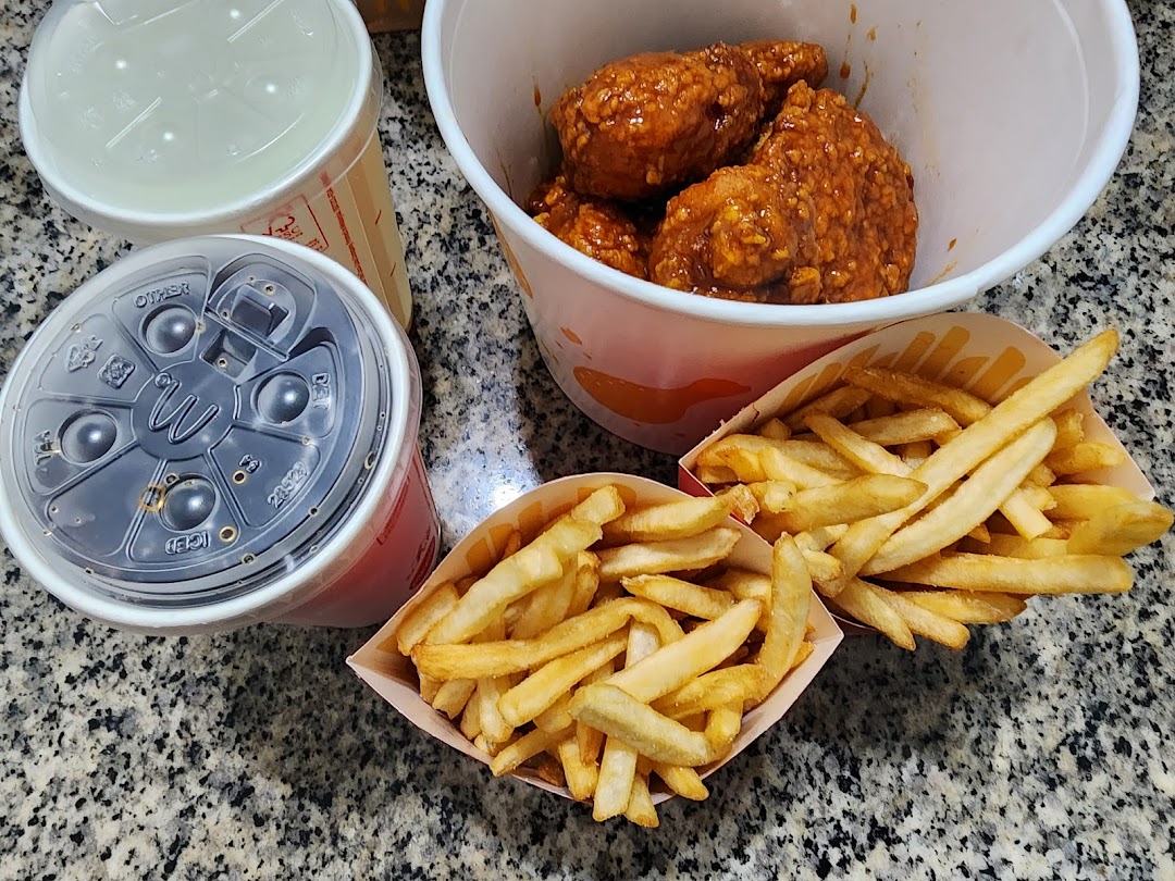 A close-up of McDonald's meal featuring fried chicken, two portions of fries, and two drinks on a speckled countertop.