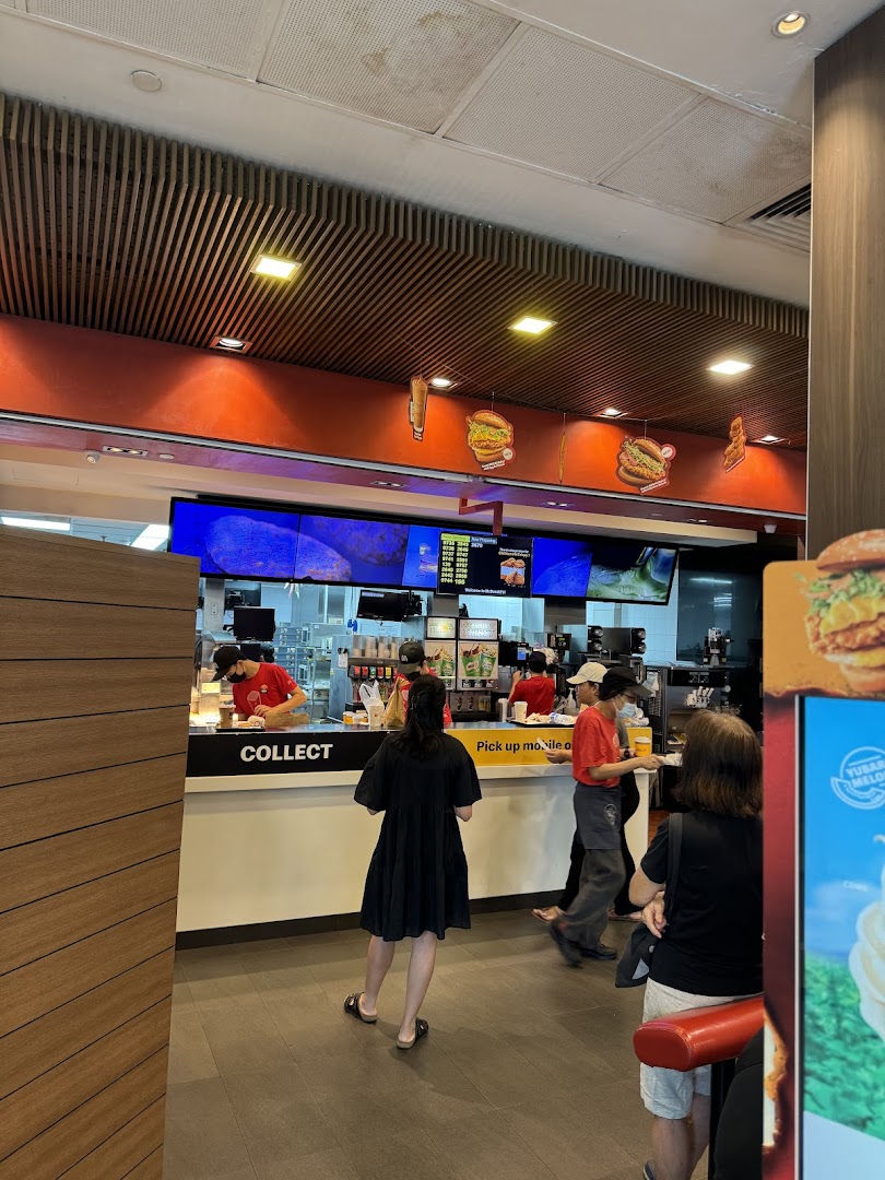 Interior view of McDonald's showing the service counter, staff, and customers waiting to collect orders.