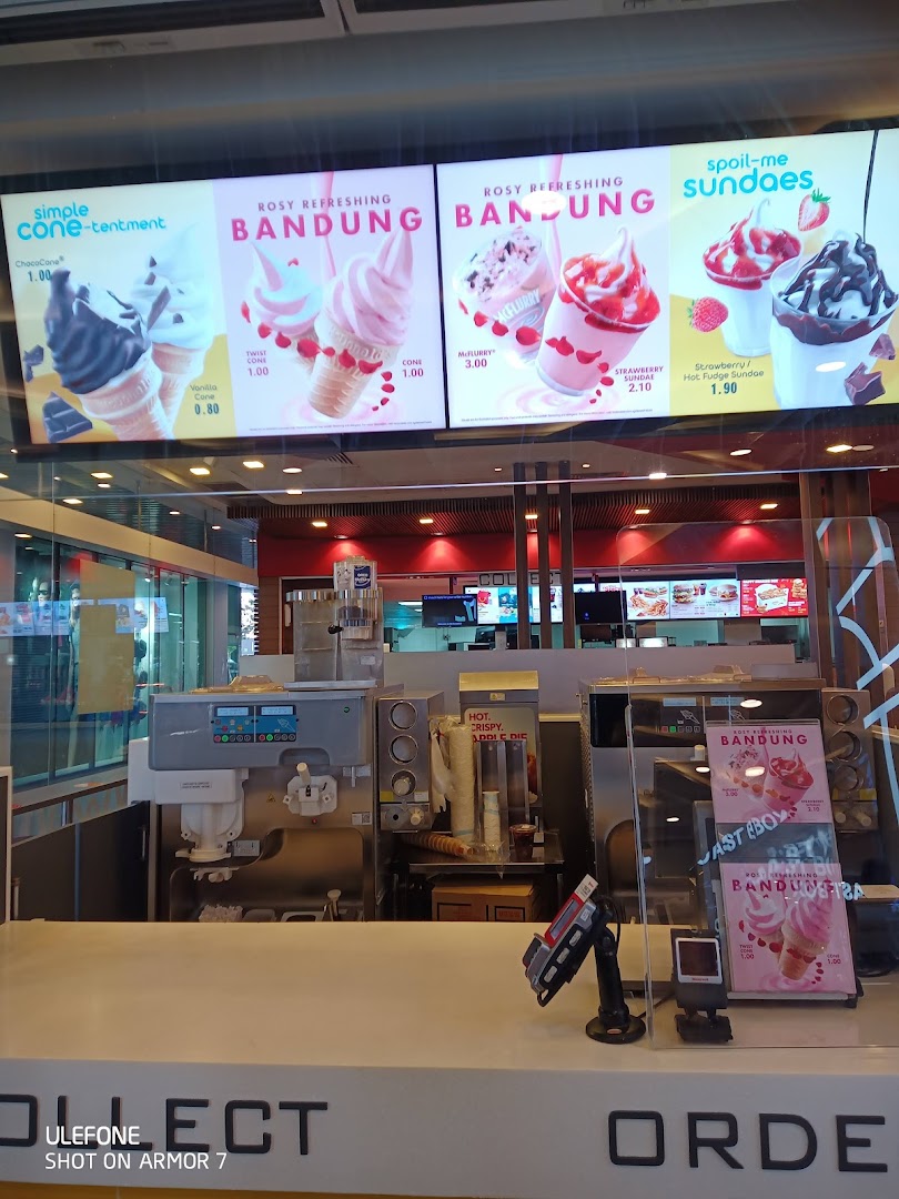 Interior view of a McDonald's counter with ice cream machines and digital menu boards displaying dessert options.
