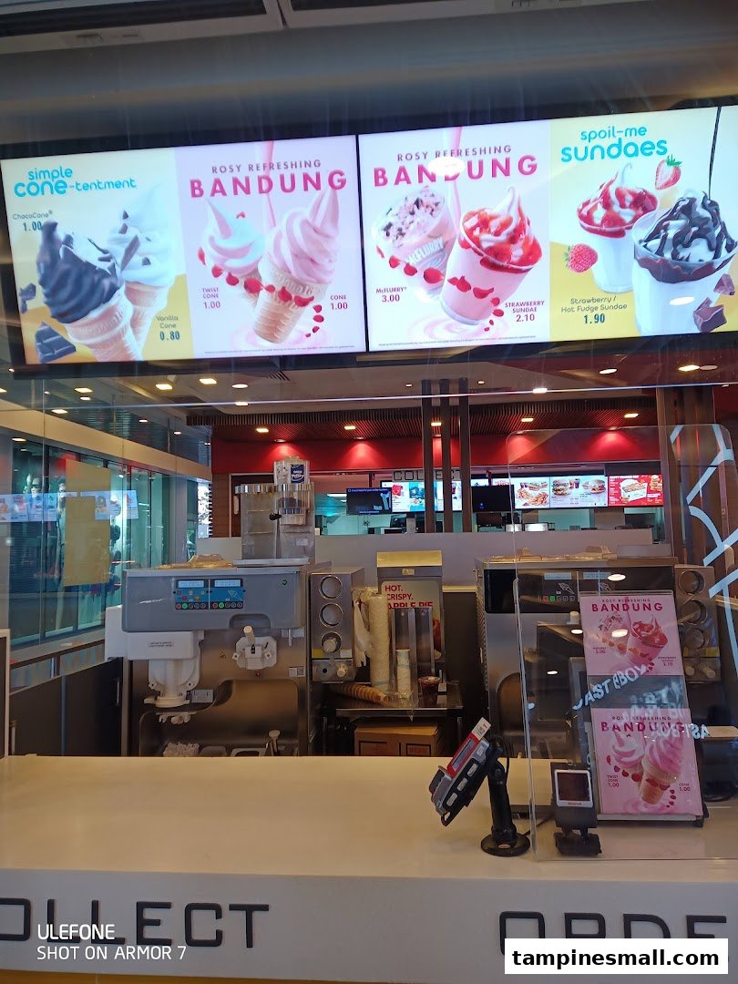 Interior view of a McDonald's counter with ice cream machines and digital menu boards displaying dessert options.