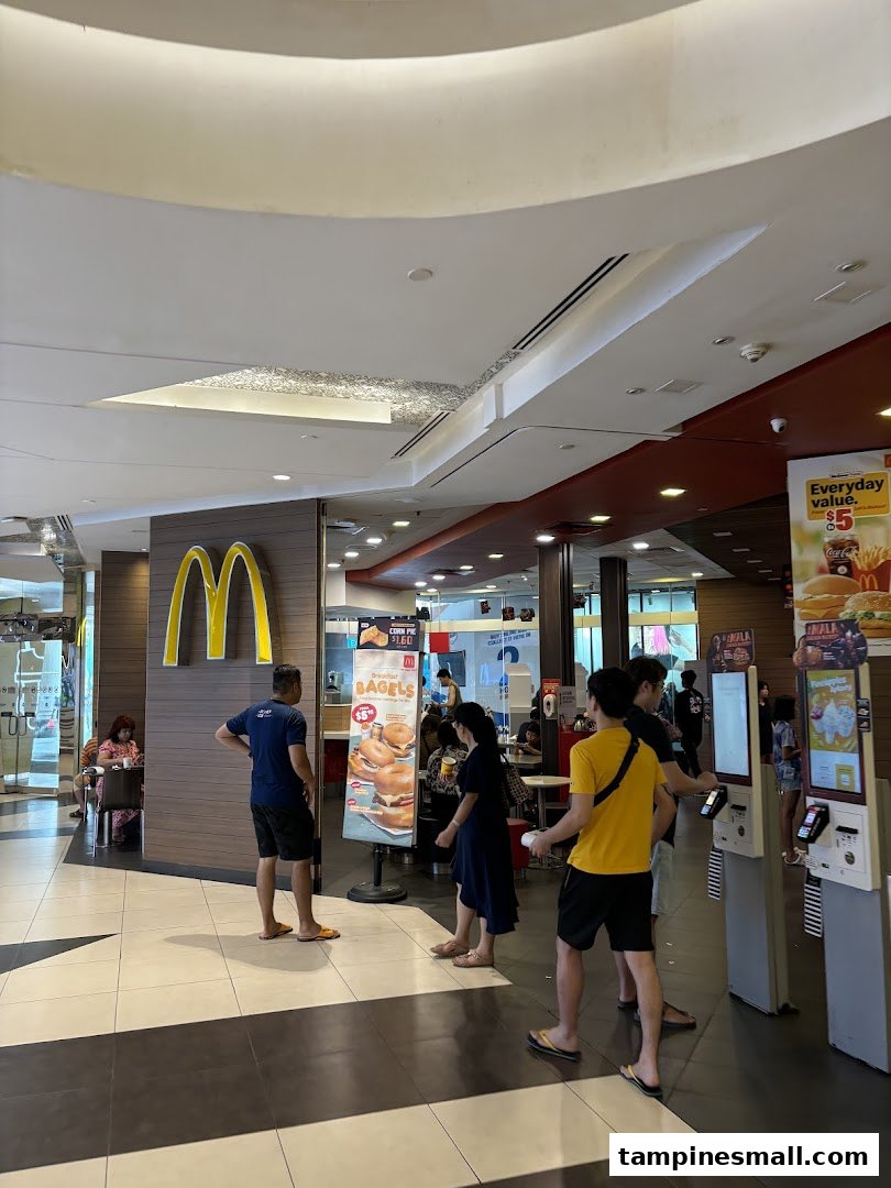 Customers gather near the entrance of McDonald's, featuring self-service kiosks and promotional signage.