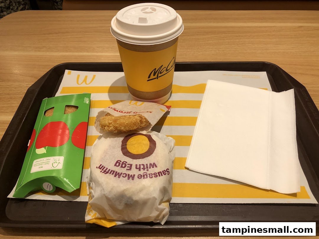 A McDonald's breakfast meal featuring a Sausage McMuffin with Egg, hash brown, and McCafé coffee.
