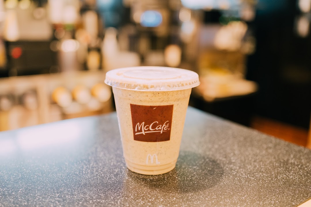 A McCafe beverage in a clear cup with a lid, sitting on a speckled counter.