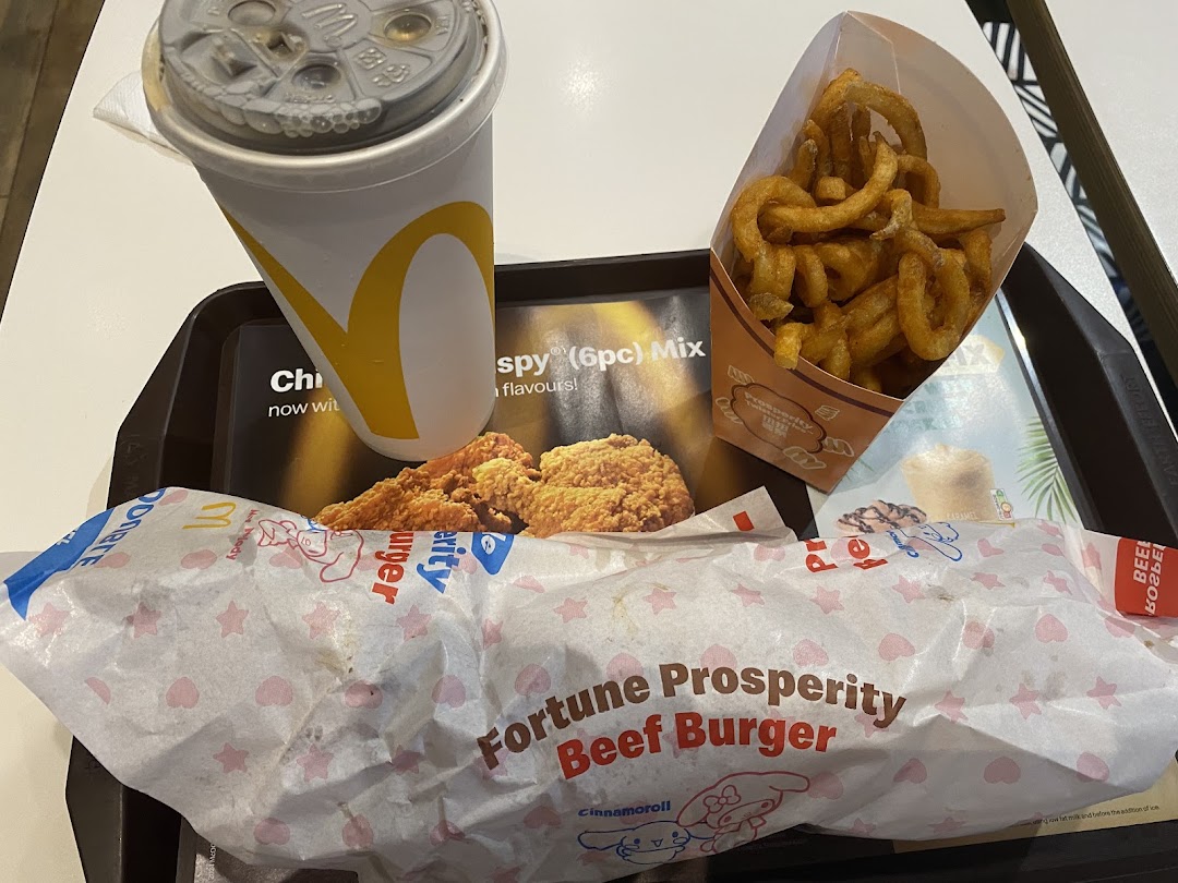 A McDonald's meal featuring a drink, curly fries, fried chicken, and a Fortune Prosperity Beef Burger.