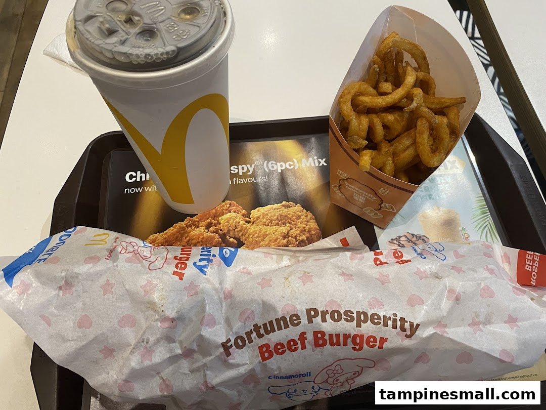 A McDonald's meal featuring a drink, curly fries, fried chicken, and a Fortune Prosperity Beef Burger.