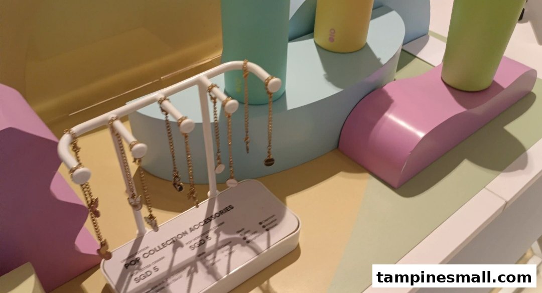 A vibrant retail display featuring gold-colored charms on a stand and colorful bottles, set against pastel props.
