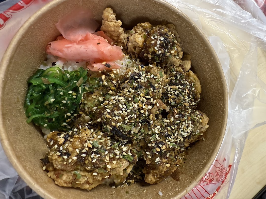 A close-up of a delicious fried chicken rice bowl with seaweed and pickled ginger.