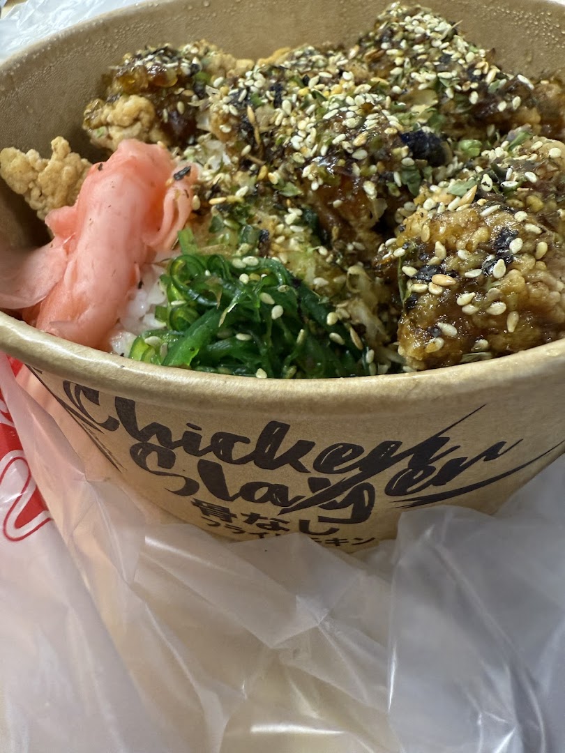 A close-up of a delicious rice bowl with crispy fried chicken, seaweed, and pickled ginger.