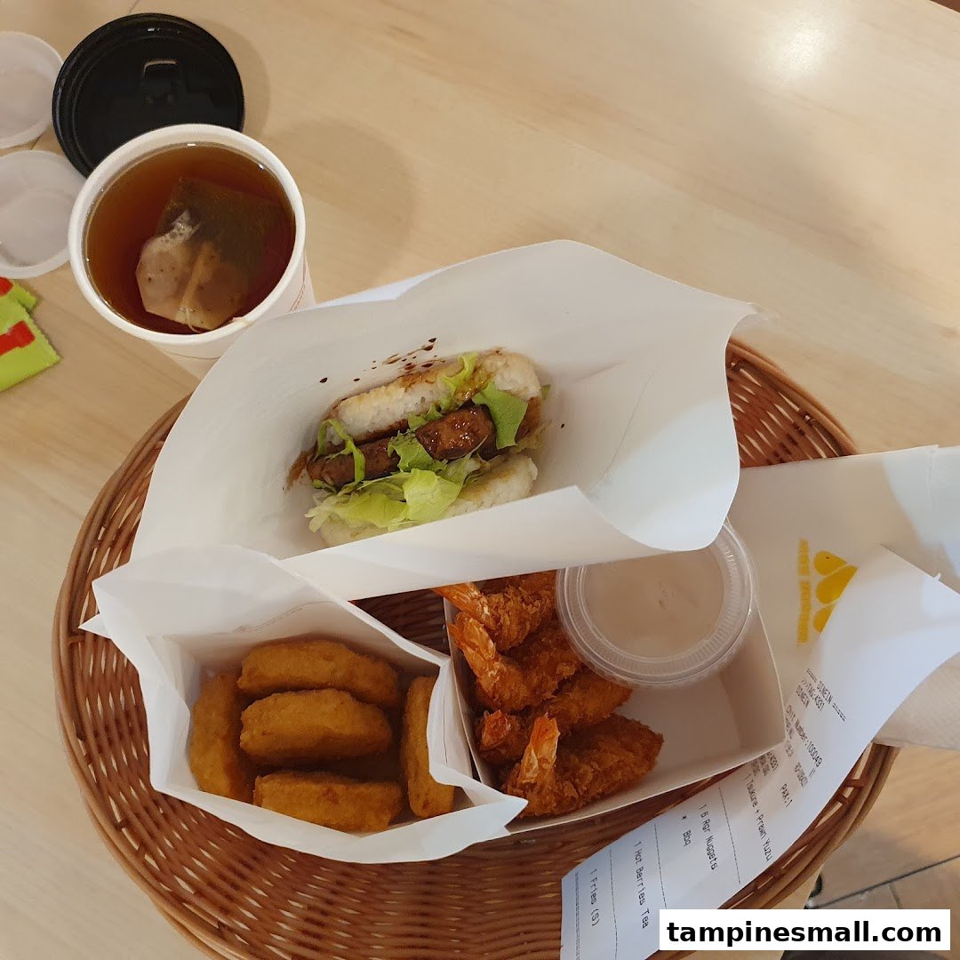 A delicious MOS Burger meal featuring a rice burger, fried shrimp, nuggets, and a hot tea on a woven tray.