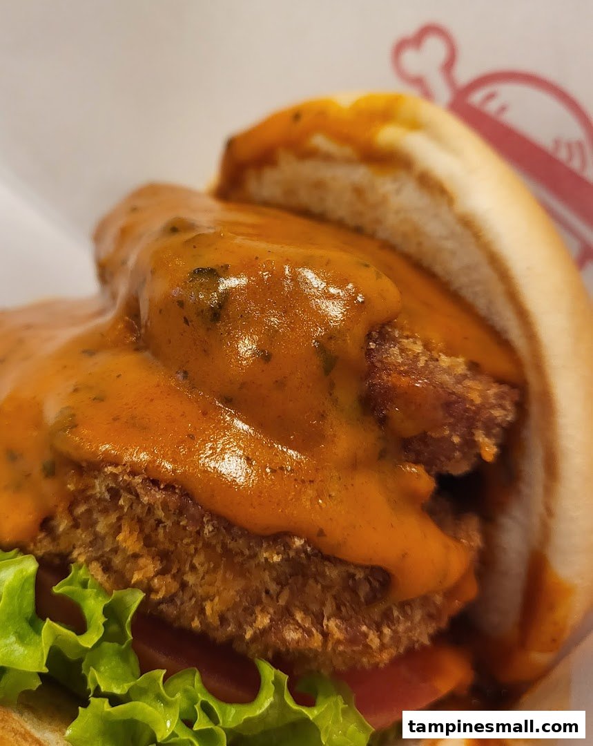 A close-up of a delicious burger with a crispy patty, fresh lettuce, and a rich orange sauce.