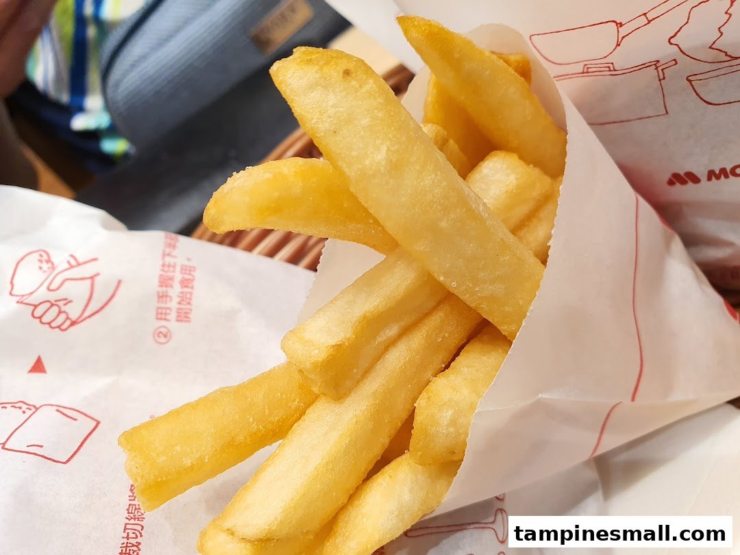 A close-up shot of golden french fries served in a white paper bag from MOS Burger.