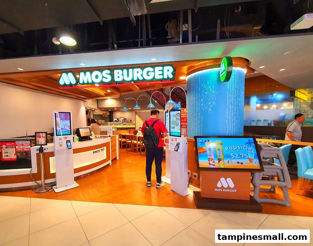 A vibrant MOS Burger shop entrance with self-order kiosks and a customer, showcasing its inviting interior.