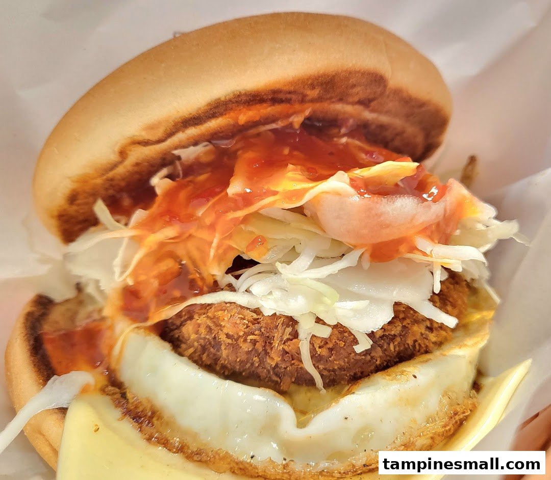 A close-up of a delicious MOS Burger with a crispy patty, fried egg, shredded cabbage, and sauce.