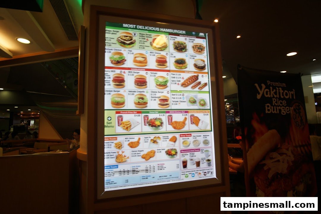 A brightly lit digital menu board at MOS Burger displaying various burgers, sides, and drinks.