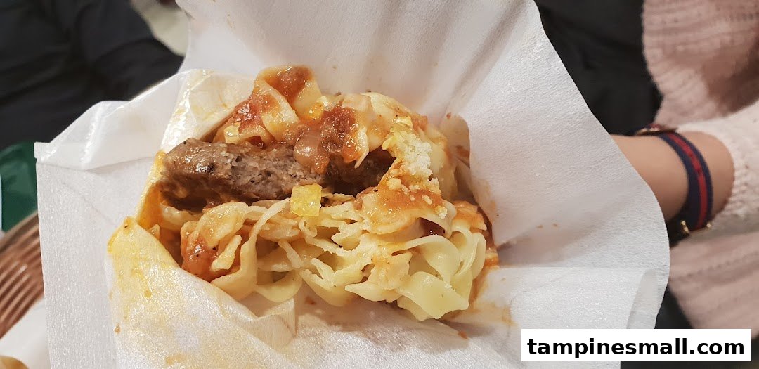 A close-up of a unique MOS Burger creation featuring a patty, pasta, and sauce wrapped in paper.
