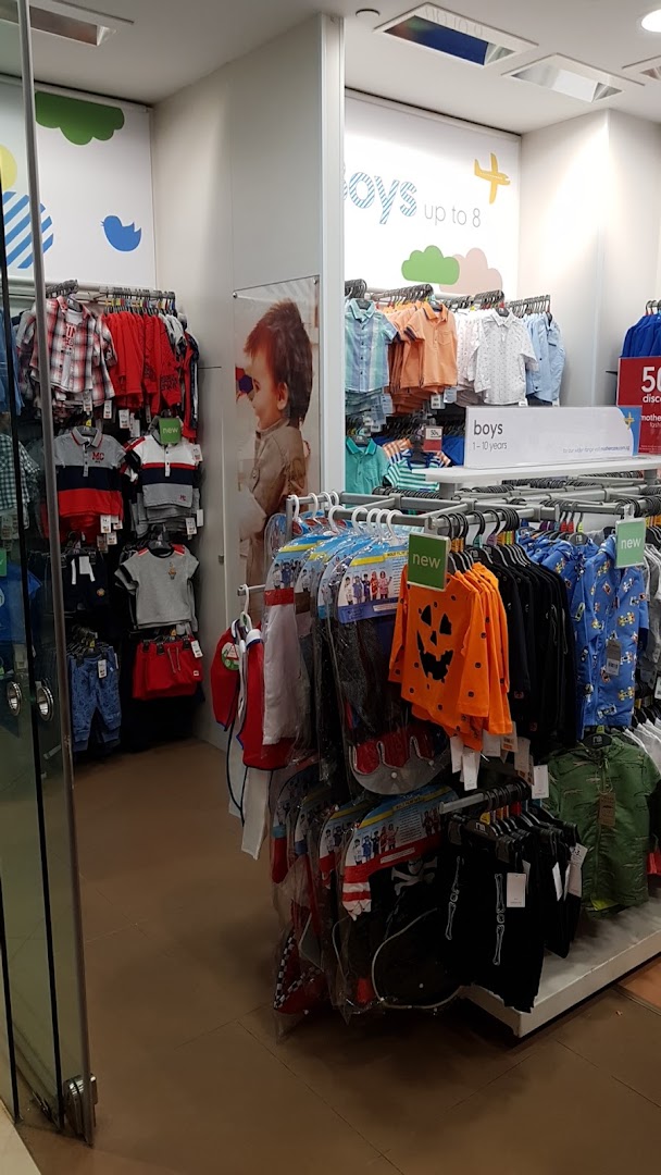 An interior view of Mothercare, showcasing a wide selection of boys' clothing on display racks.