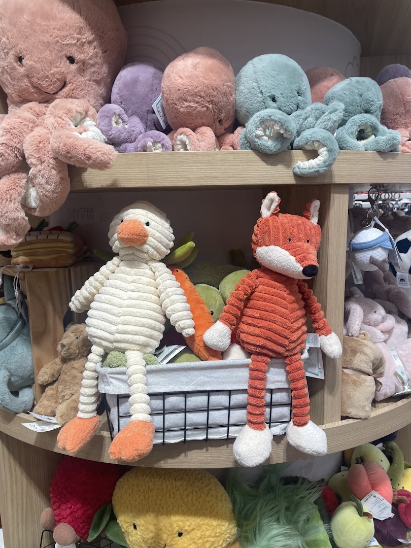 A vibrant display of colorful plush toys, including octopuses, a duck, and a fox, on wooden shelves.
