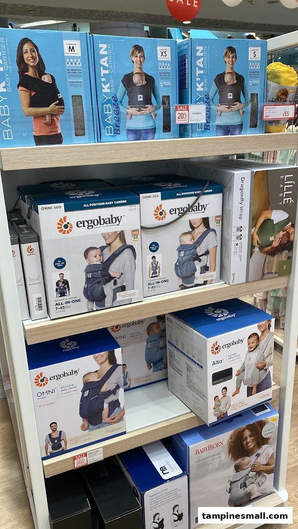 A retail display shelf at Mothercare showcasing various baby carriers and accessories.