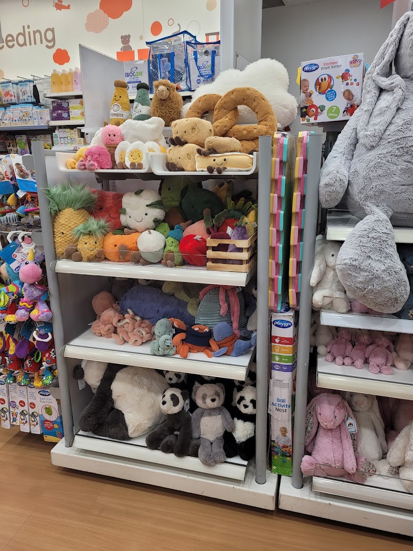 A vibrant display of diverse plush toys, including food-themed and animal characters, on shelves inside Mothercare.