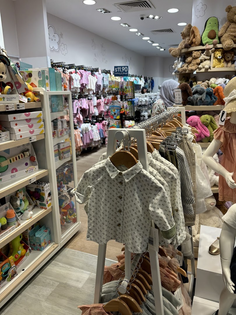 An interior view of Mothercare, showcasing a wide array of baby clothing, toys, and plush animals.