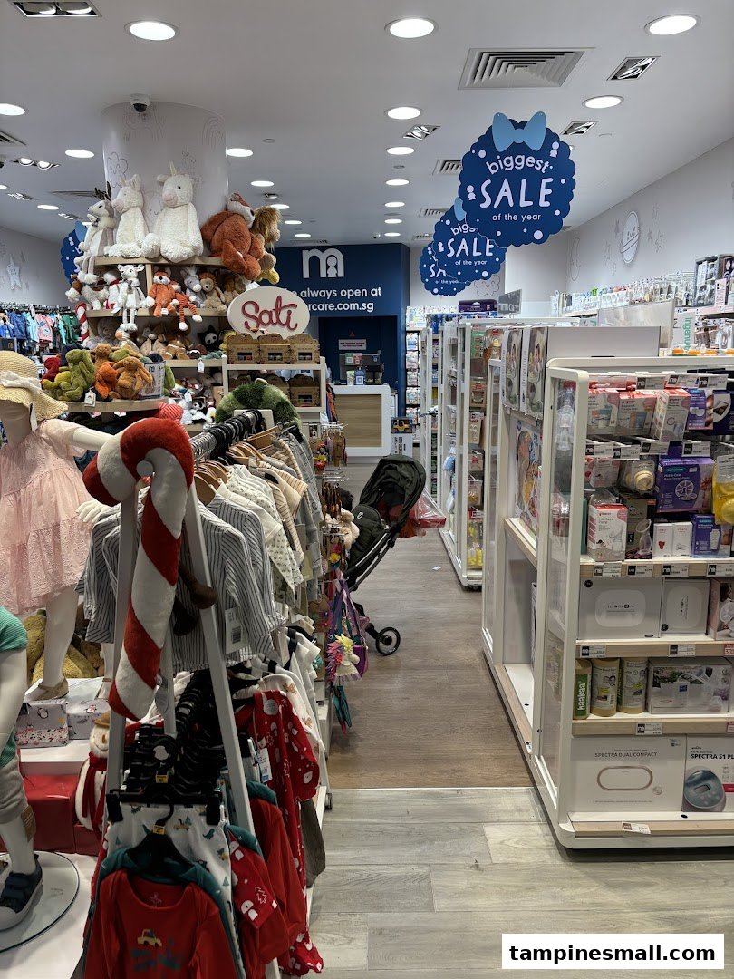 An interior view of Mothercare, showcasing baby clothing, plush toys, and essential baby products, with sale signs visible.