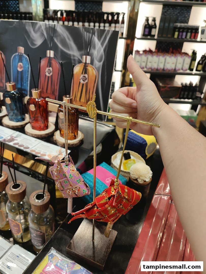 A hand gives a thumbs-up over a display of colorful diffusers and decorative items at Mt.Sapola.