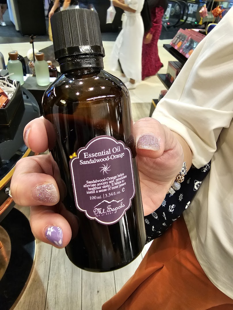 A person holds a bottle of Mt.Sapola Sandalwood-Orange Essential Oil inside the store.