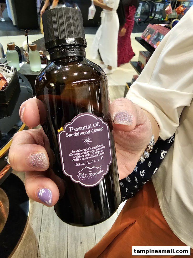 A person holds a bottle of Mt.Sapola Sandalwood-Orange Essential Oil inside the store.