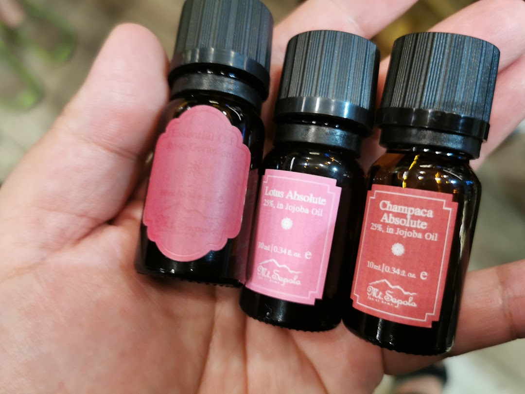 A hand holding three small bottles of Mt.Sapola essential oils.