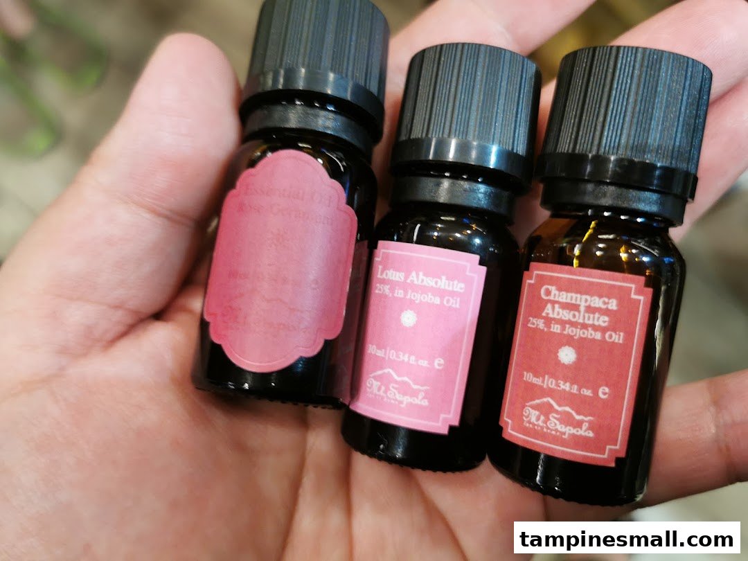 A hand holding three small bottles of Mt.Sapola essential oils.