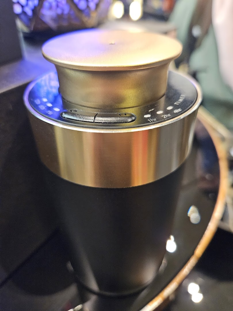 Close-up of a sleek black and gold essential oil diffuser with visible timer settings.