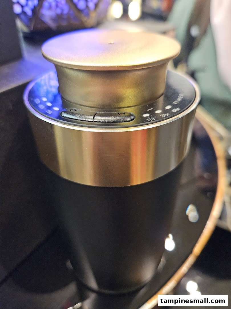 Close-up of a sleek black and gold essential oil diffuser with visible timer settings.