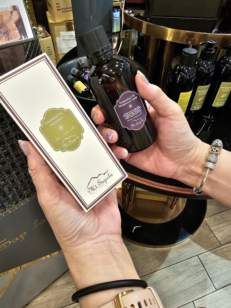 Hands holding Mt.Sapola essential oil products, including Signature and Sandalwood-Orange blends.