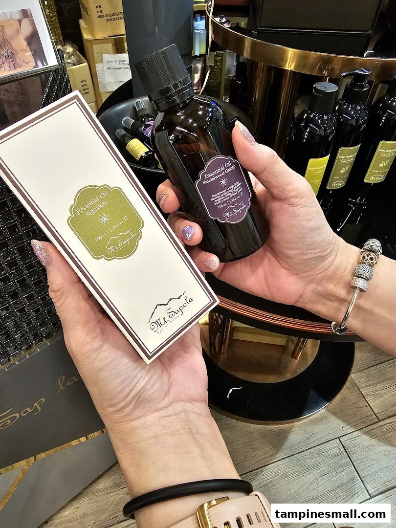 Hands holding Mt.Sapola essential oil products, including Signature and Sandalwood-Orange blends.