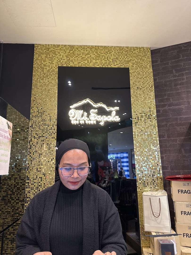 A shop employee at the counter with the Mt. Sapola logo displayed prominently in the background.