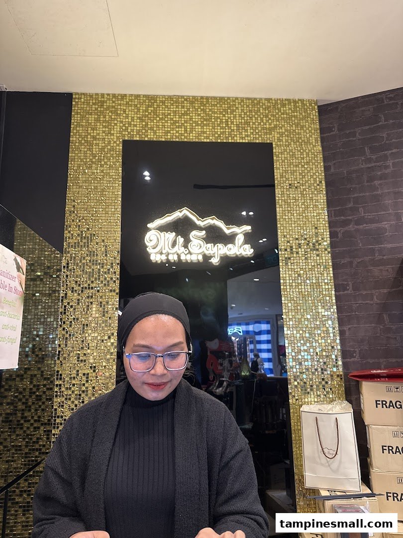 A shop employee at the counter with the Mt. Sapola logo displayed prominently in the background.
