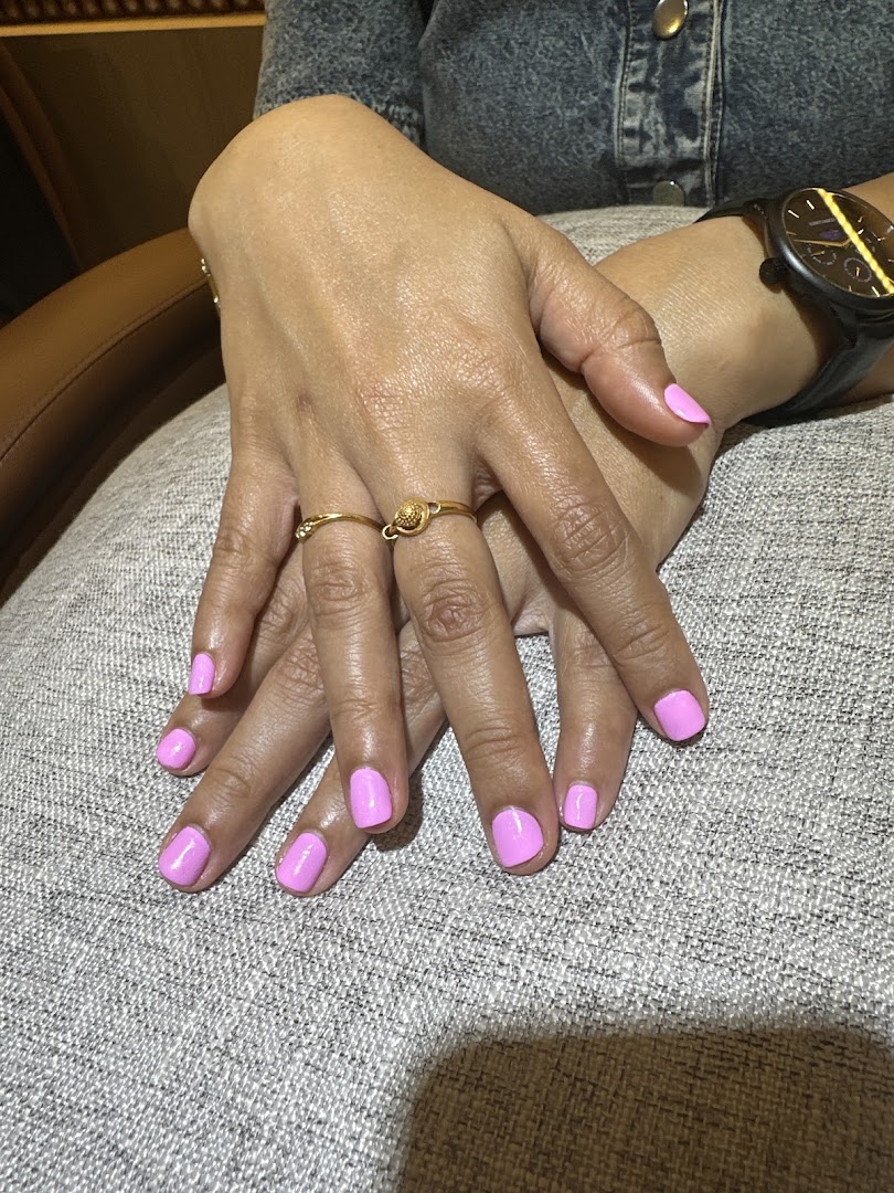 Close-up of hands with freshly painted bright pink nails, showcasing a nail spa service.