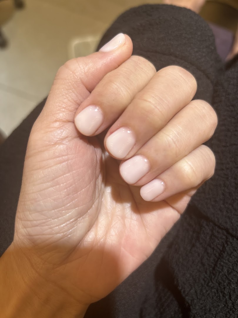 A close-up of a hand showcasing freshly manicured nails with a light pink polish.