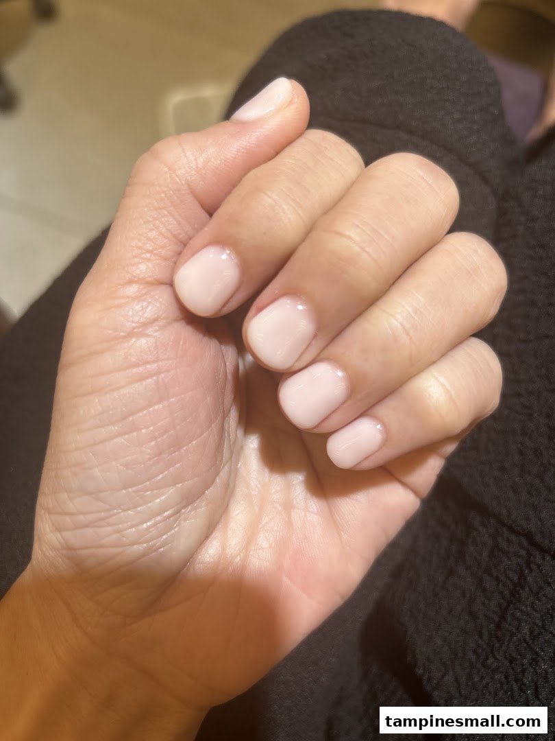 A close-up of a hand showcasing freshly manicured nails with a light pink polish.