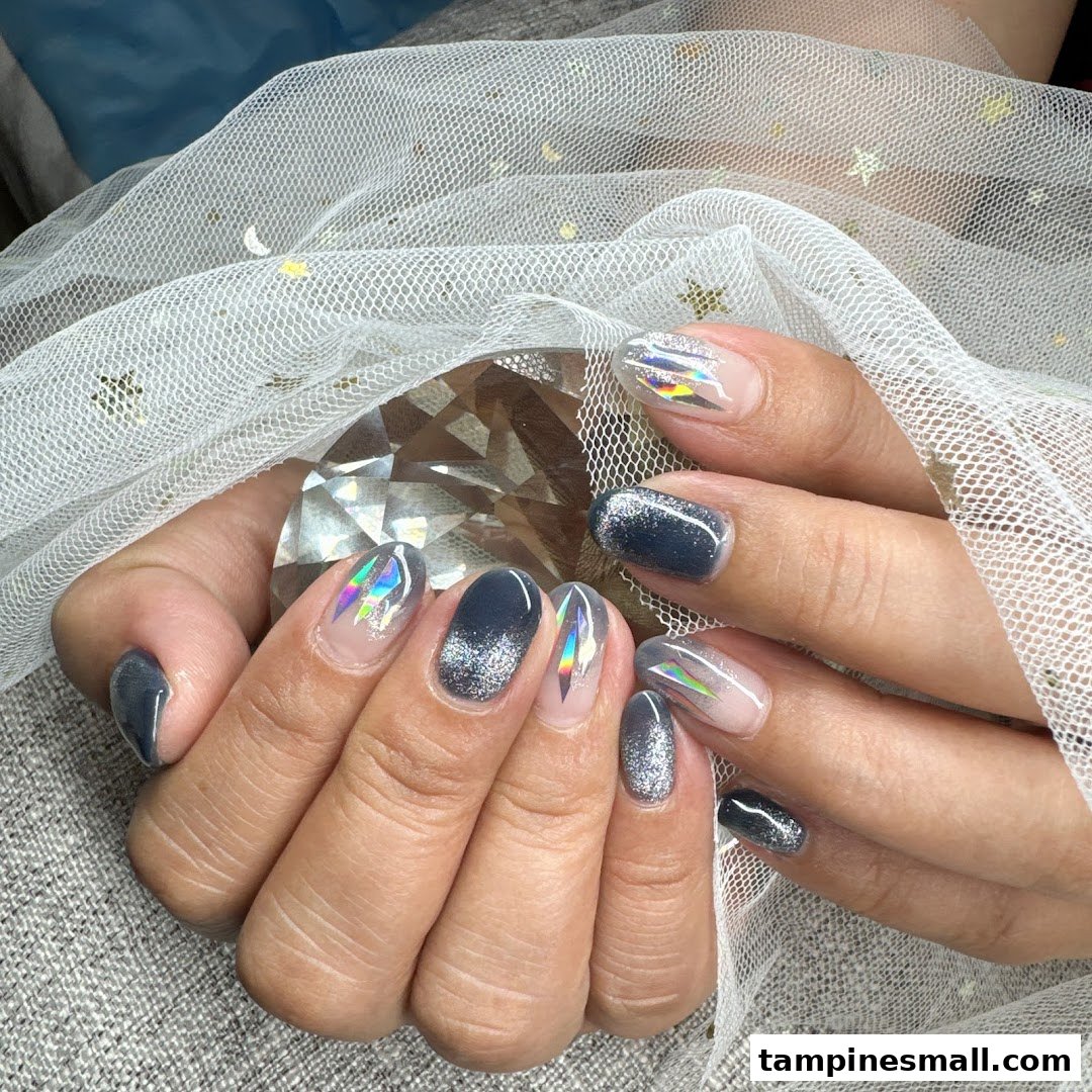 Close-up of hands showcasing a stylish grey and glitter nail design with holographic accents.