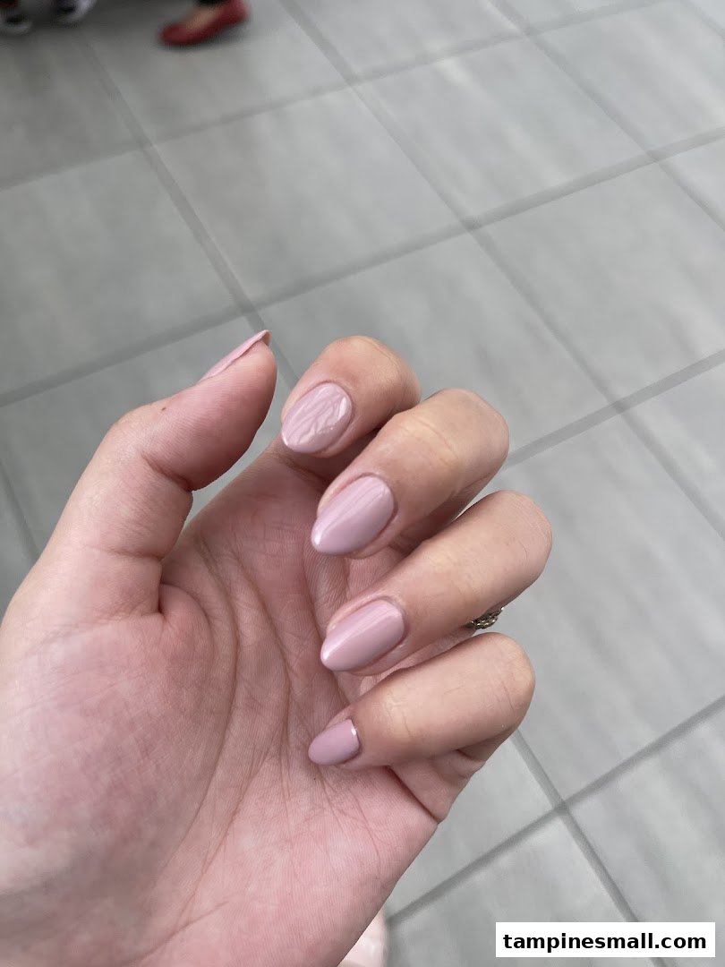 A hand showcasing freshly manicured nails with light pink polish, highlighting the salon's service quality.