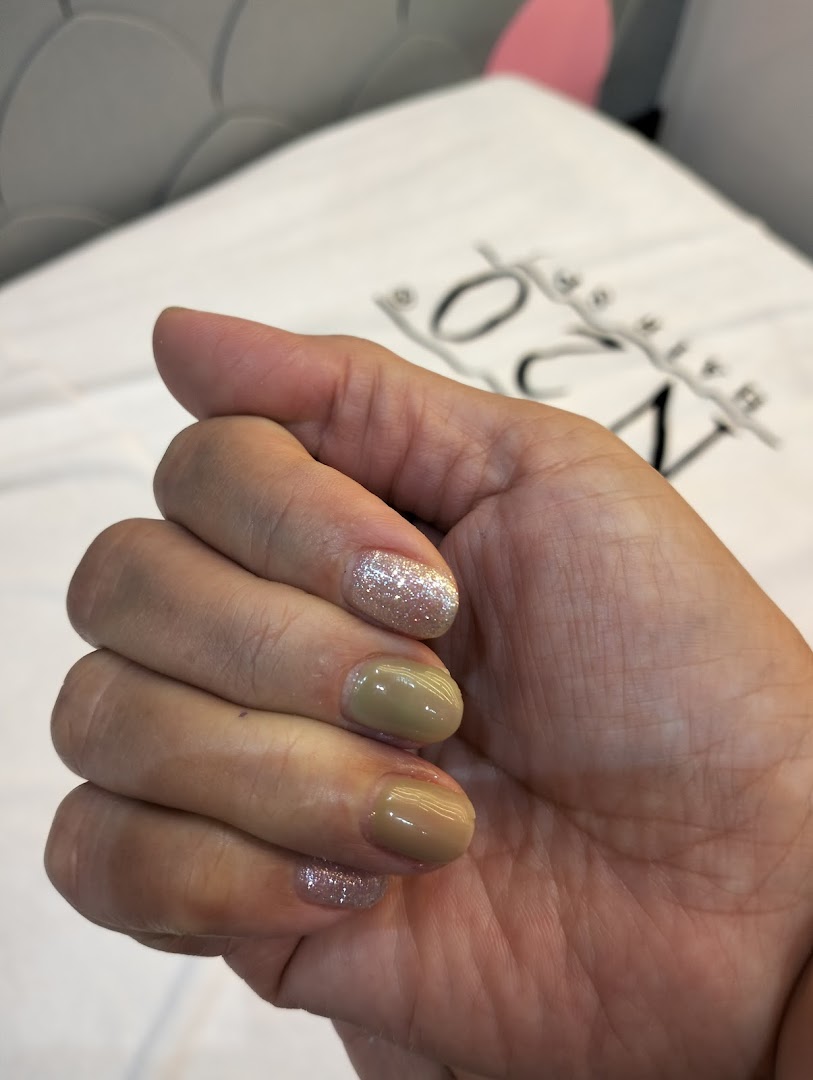 A close-up of a hand showcasing a fresh manicure with glitter and solid polish.