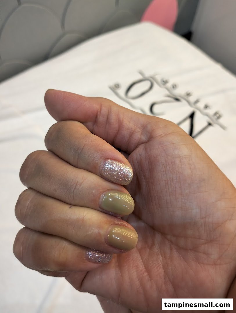 A close-up of a hand showcasing a fresh manicure with glitter and solid polish.