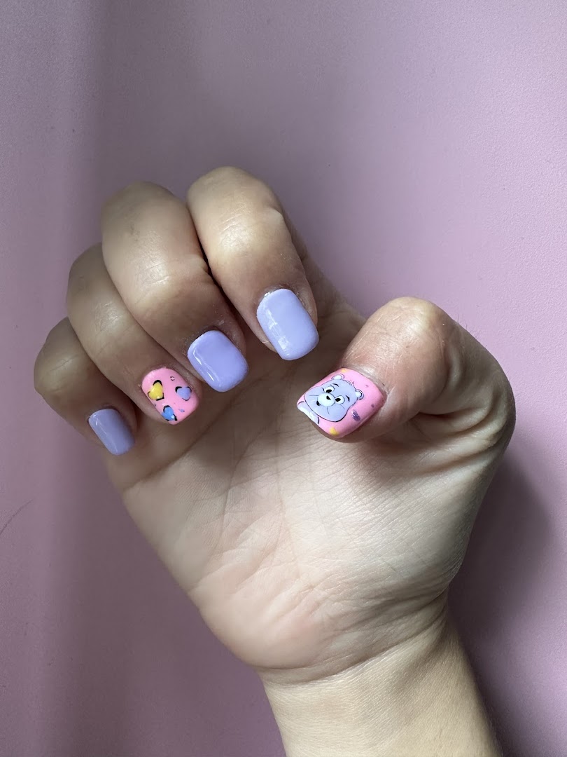 A hand showcasing vibrant purple and pink nails with playful cartoon and heart designs.