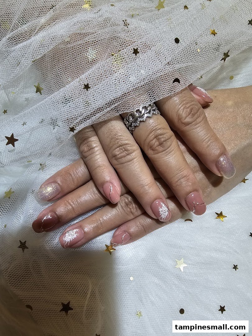 Close-up of hands showcasing beautifully manicured nails with intricate designs and glitter accents.