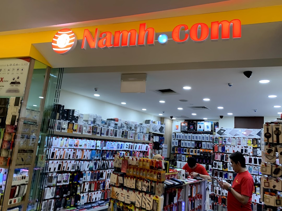 The entrance of Namh.com, a tech accessories shop, displaying numerous phone cases and gadgets, with staff inside.