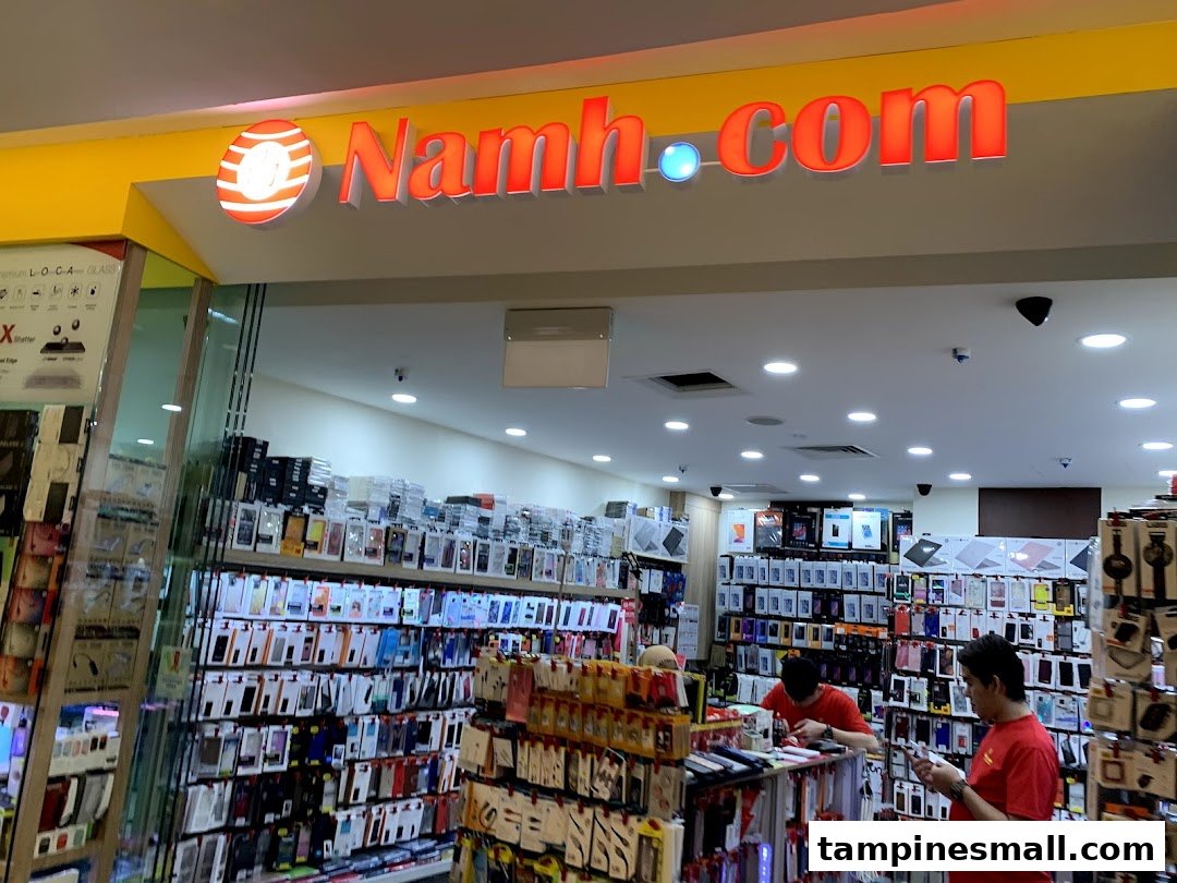 The entrance of Namh.com, a tech accessories shop, displaying numerous phone cases and gadgets, with staff inside.