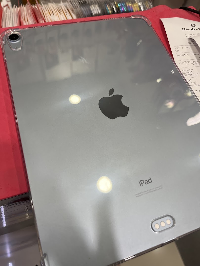 A silver iPad with a clear case and a retail receipt from Namh.com visible on a red surface.