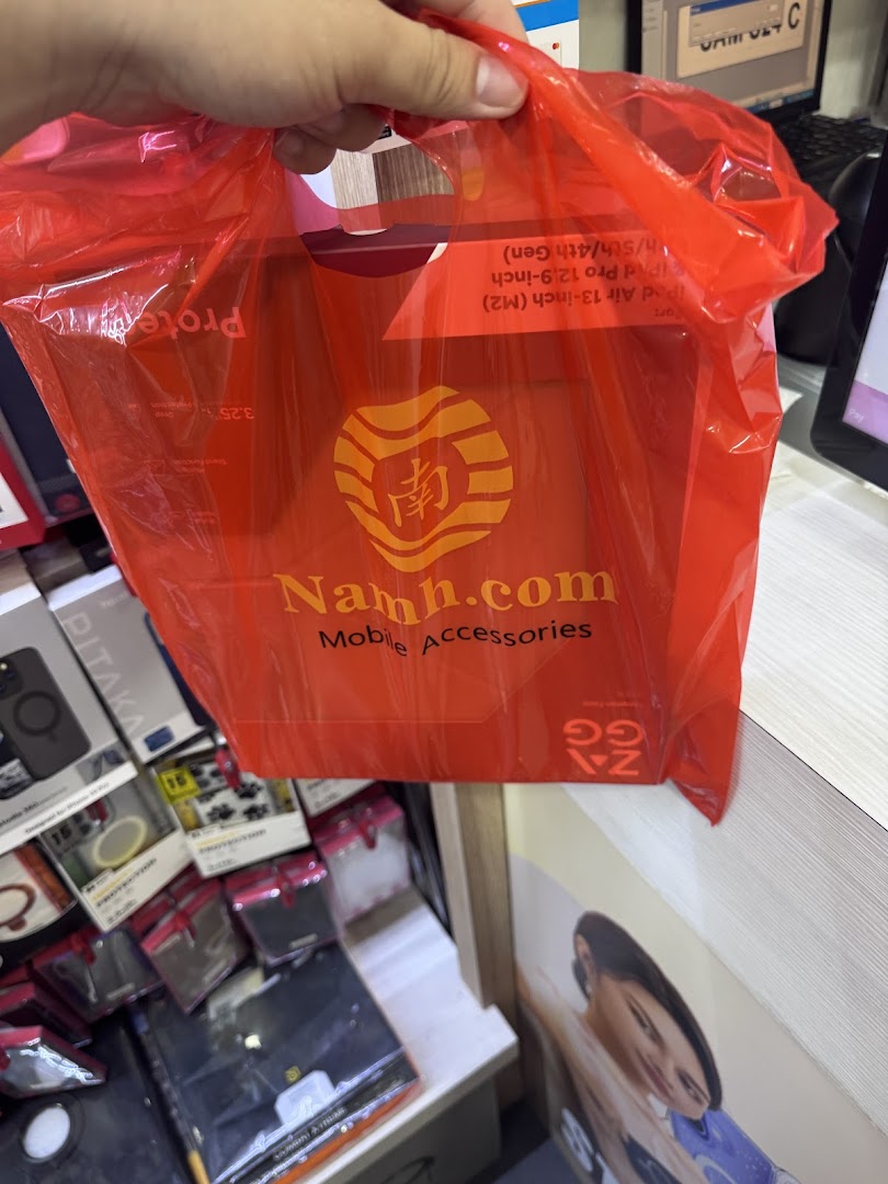 A hand holds a red Namh.com shopping bag, showcasing mobile accessories and branding.