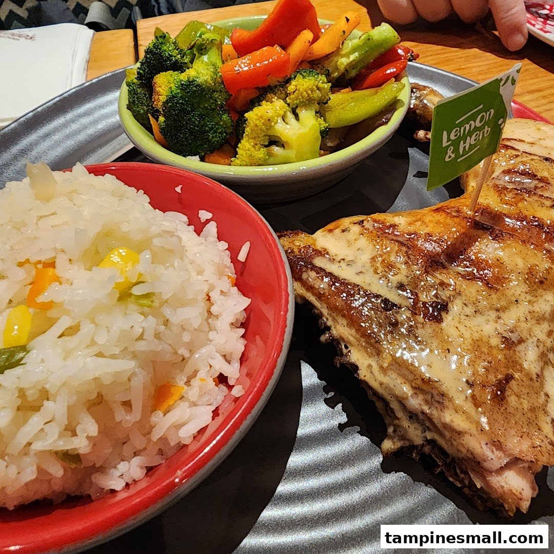 A plate of Nando's flame-grilled PERi-PERi chicken with rice and roasted vegetables, featuring a 'Lemon & Herb' flag.